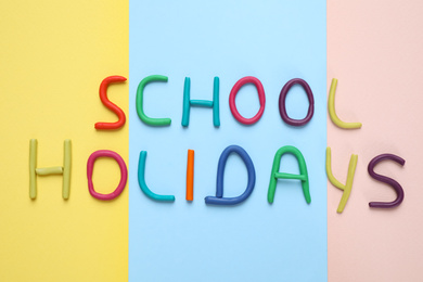 Photo of Phrase School Holidays made of modeling clay on color background, top view