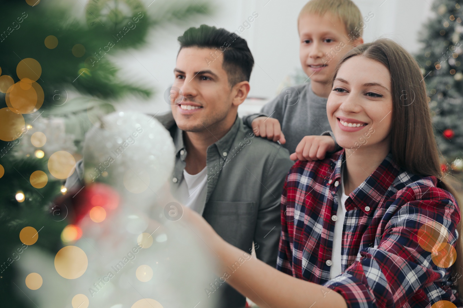 Photo of Happy family with cute child decorating Christmas tree together at home