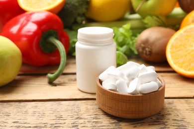 Photo of Dietary supplements. Plastic bottle, pills in bowl and food products on wooden table