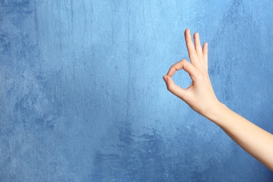 Photo of Woman showing okay gesture on color background, space for text