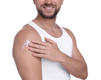 Man applying sun protection cream onto his shoulder against white background, closeup