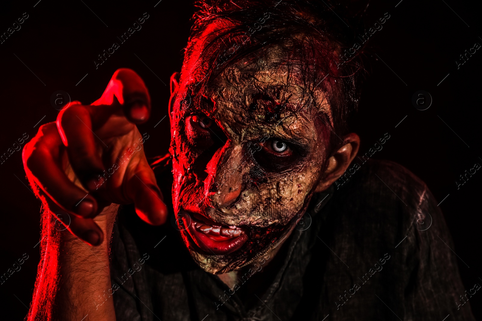 Photo of Scary zombie on dark background, closeup. Halloween monster