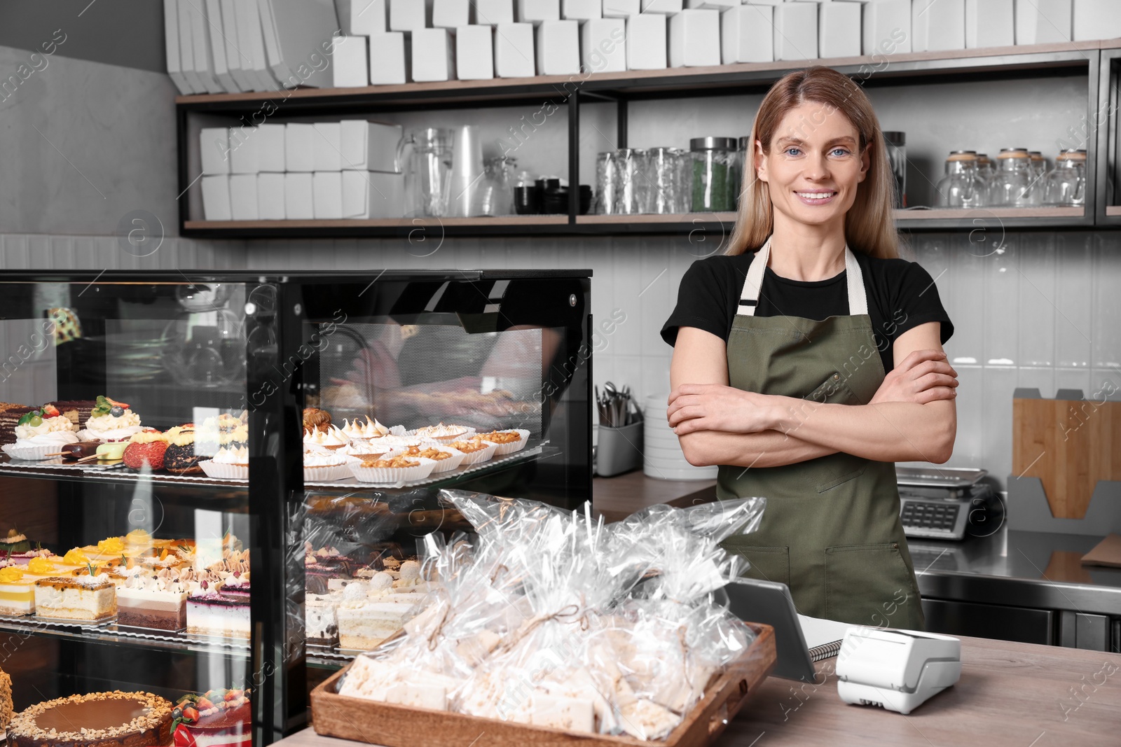 Photo of Happy seller at cashier desk near showcase in store