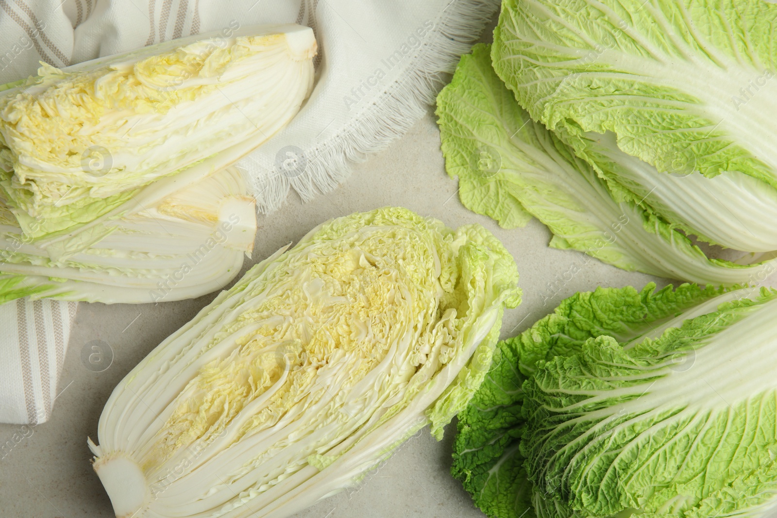 Photo of Whole and cut fresh Chinese cabbages on light grey table, flat lay
