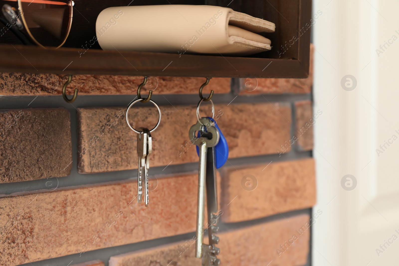 Photo of Hanger for keys with accessories on brick wall