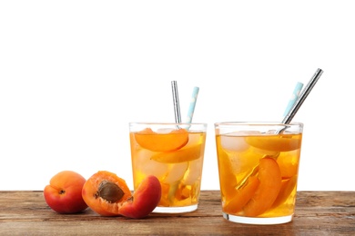 Photo of Delicious refreshing drink with apricot on wooden table against white background