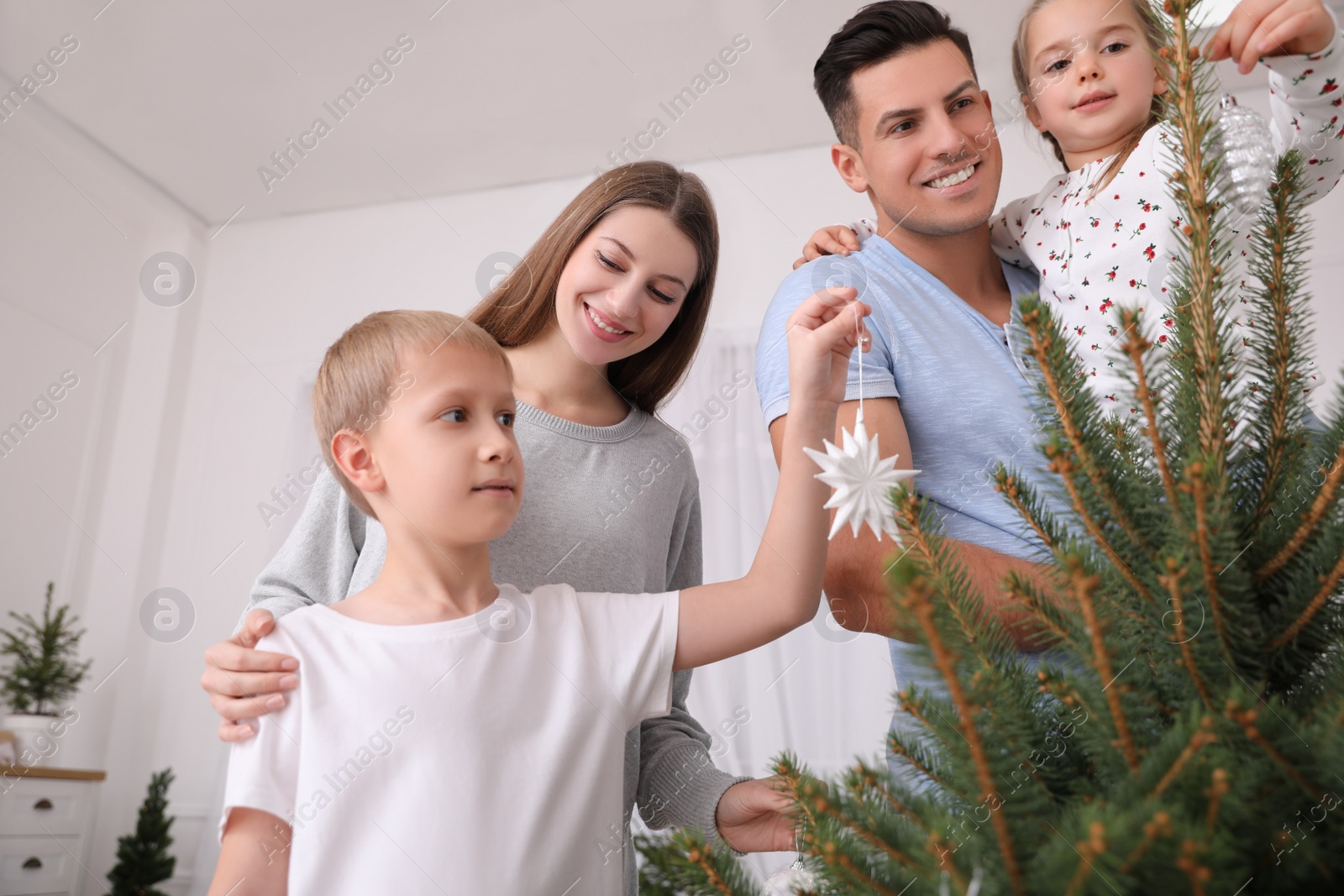 Photo of Happy family with cute children decorating Christmas tree together at home