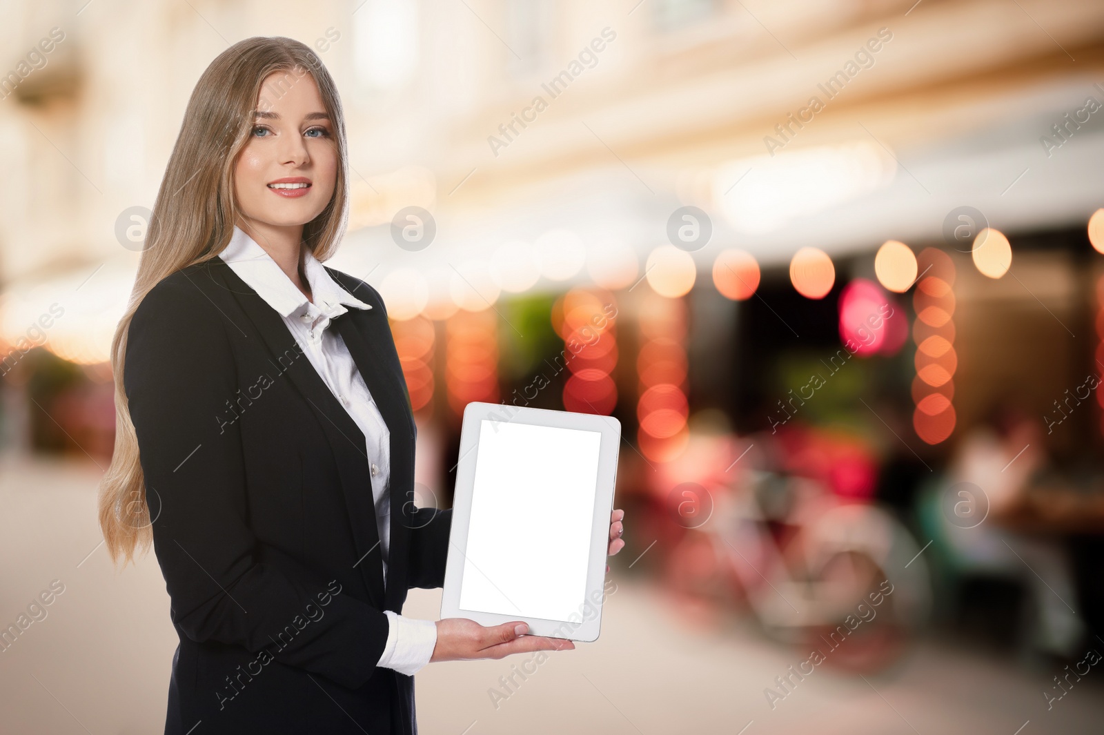 Image of Portrait of hostess in uniform with tablet and blurred view of cafe with outdoor terrace. Space for text