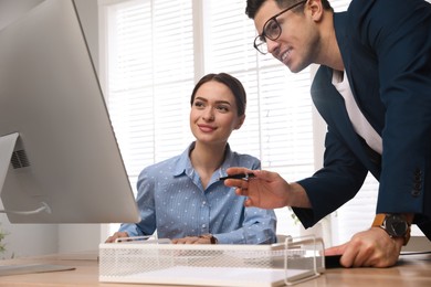 Businessman helping intern with work in office