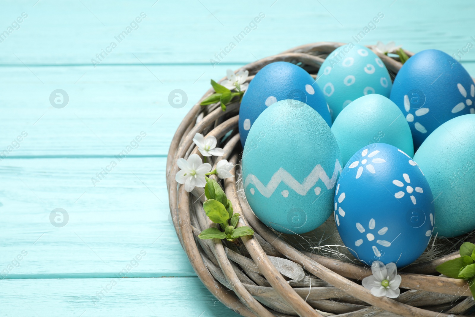 Photo of Nest with Easter eggs on light blue wooden background, closeup