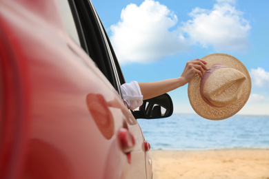 Woman waving from car on beach, closeup. Summer vacation trip