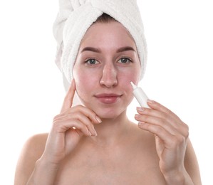 Young woman with acne problem applying cosmetic product onto her skin on white background