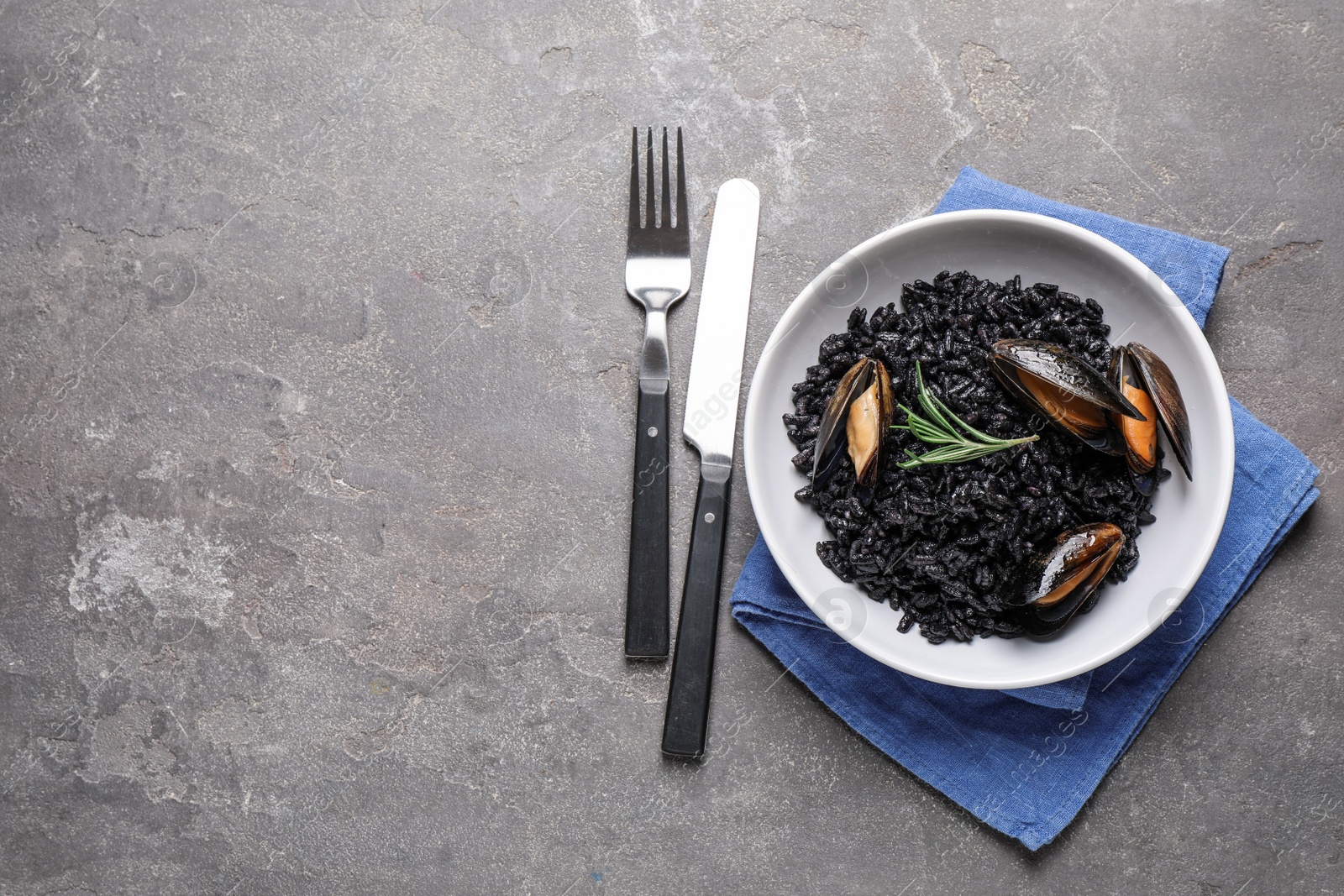 Photo of Delicious black risotto with seafood on grey table, flat lay. Space for text