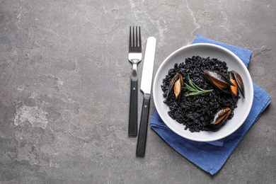 Delicious black risotto with seafood on grey table, flat lay. Space for text