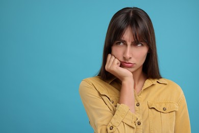 Resentful woman on light blue background, space for text