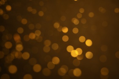 Photo of Blurred view of golden glitter on dark background. Bokeh effect