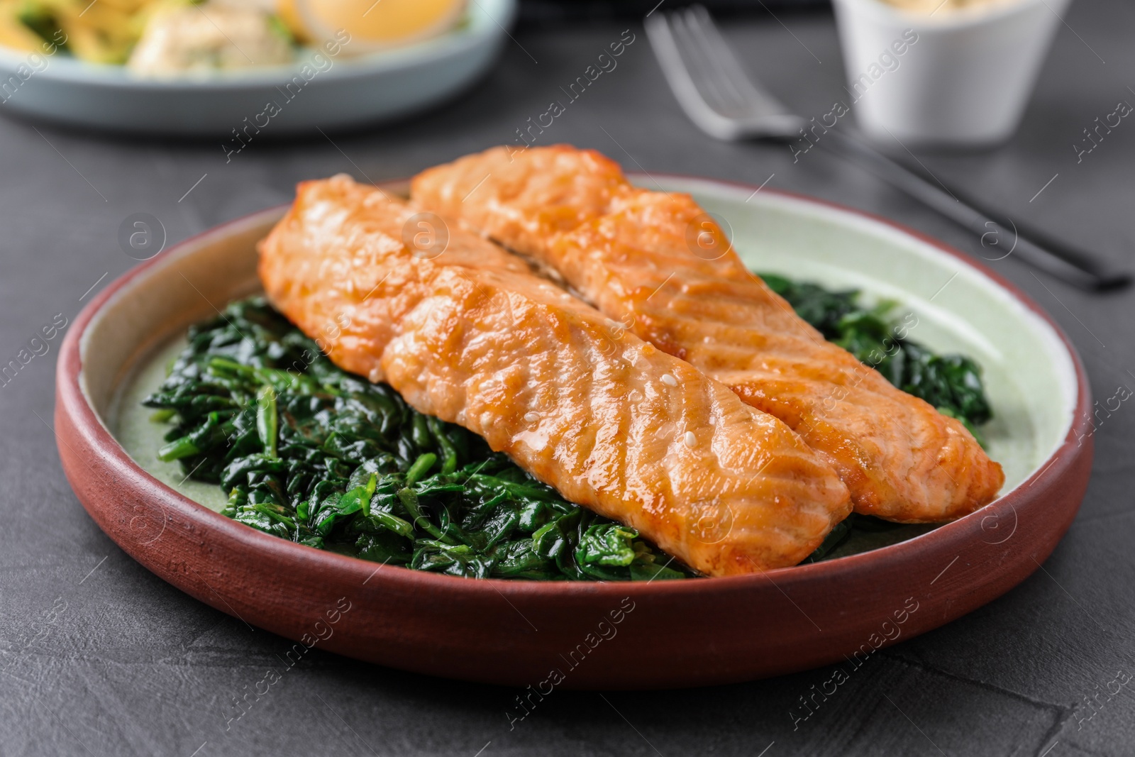 Photo of Tasty salmon with spinach on grey table