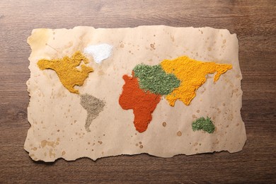 World map of different spices on wooden table, top view