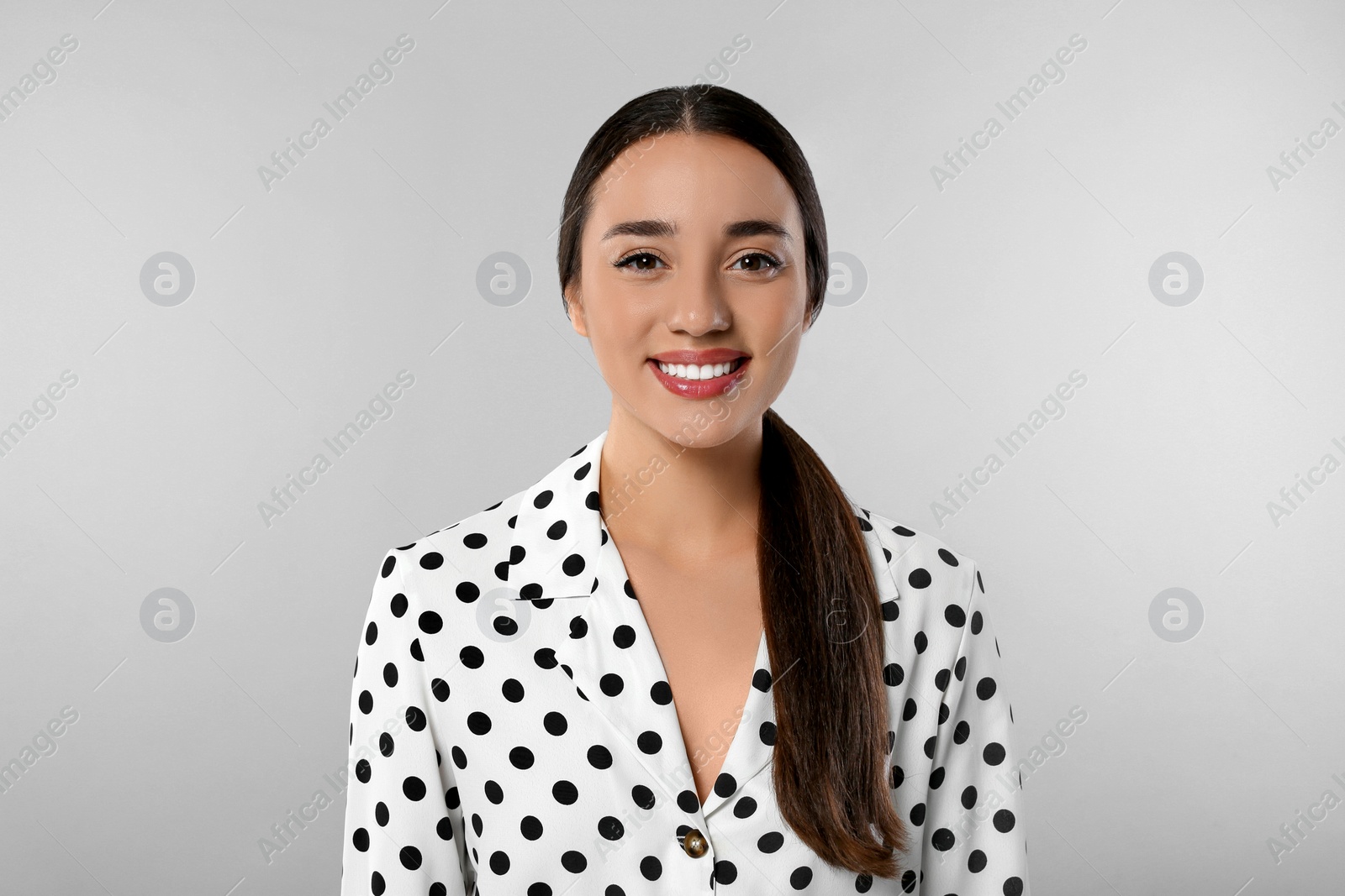 Photo of Portrait of beautiful young woman in polka dot blouse on light grey background