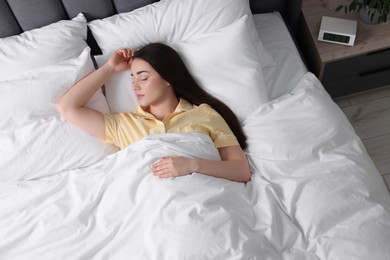 Photo of Beautiful young woman sleeping in soft bed at home, above view