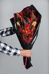 Man with beautiful food bouquet on light grey background, closeup