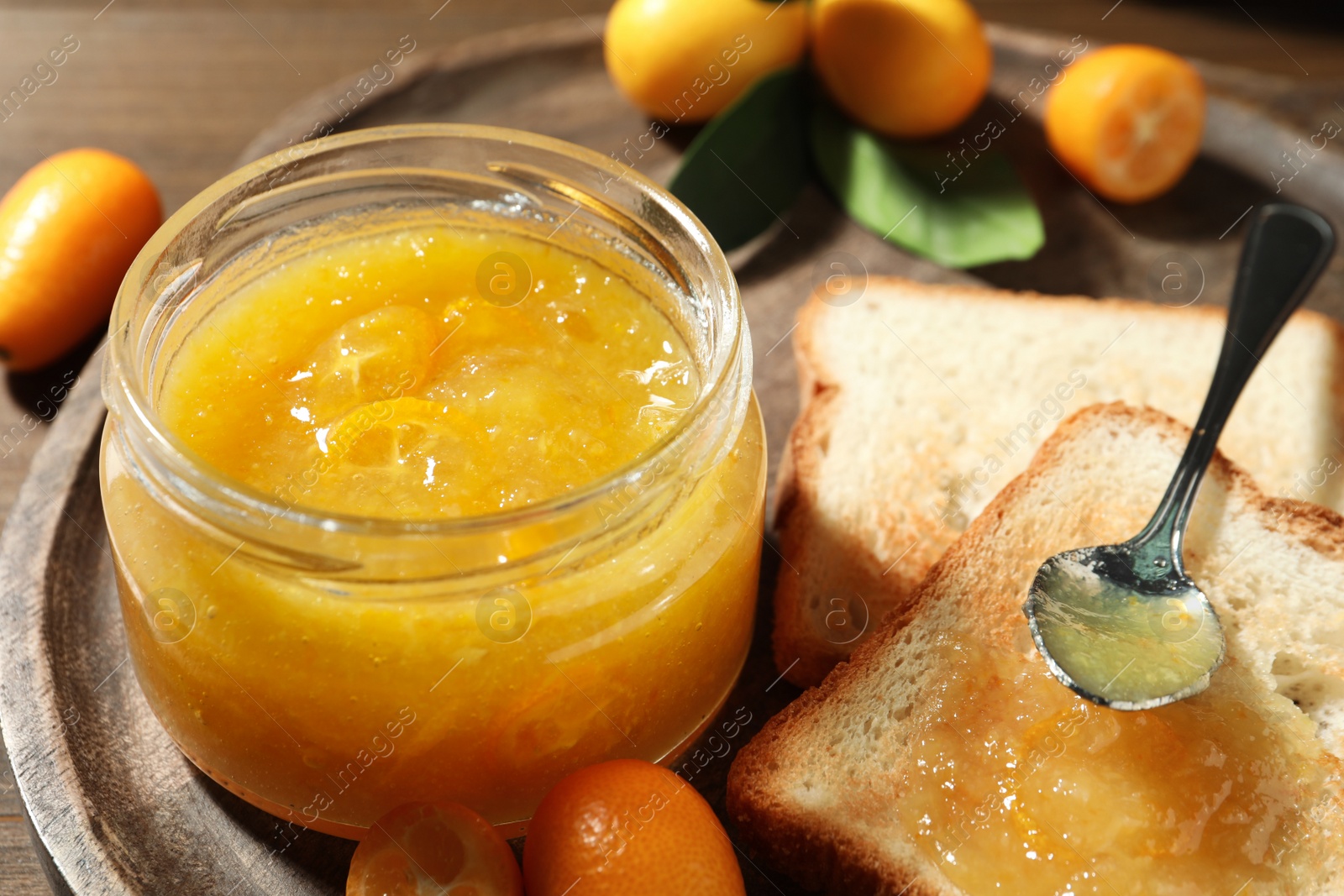 Photo of Delicious kumquat jam and sandwich on wooden tray