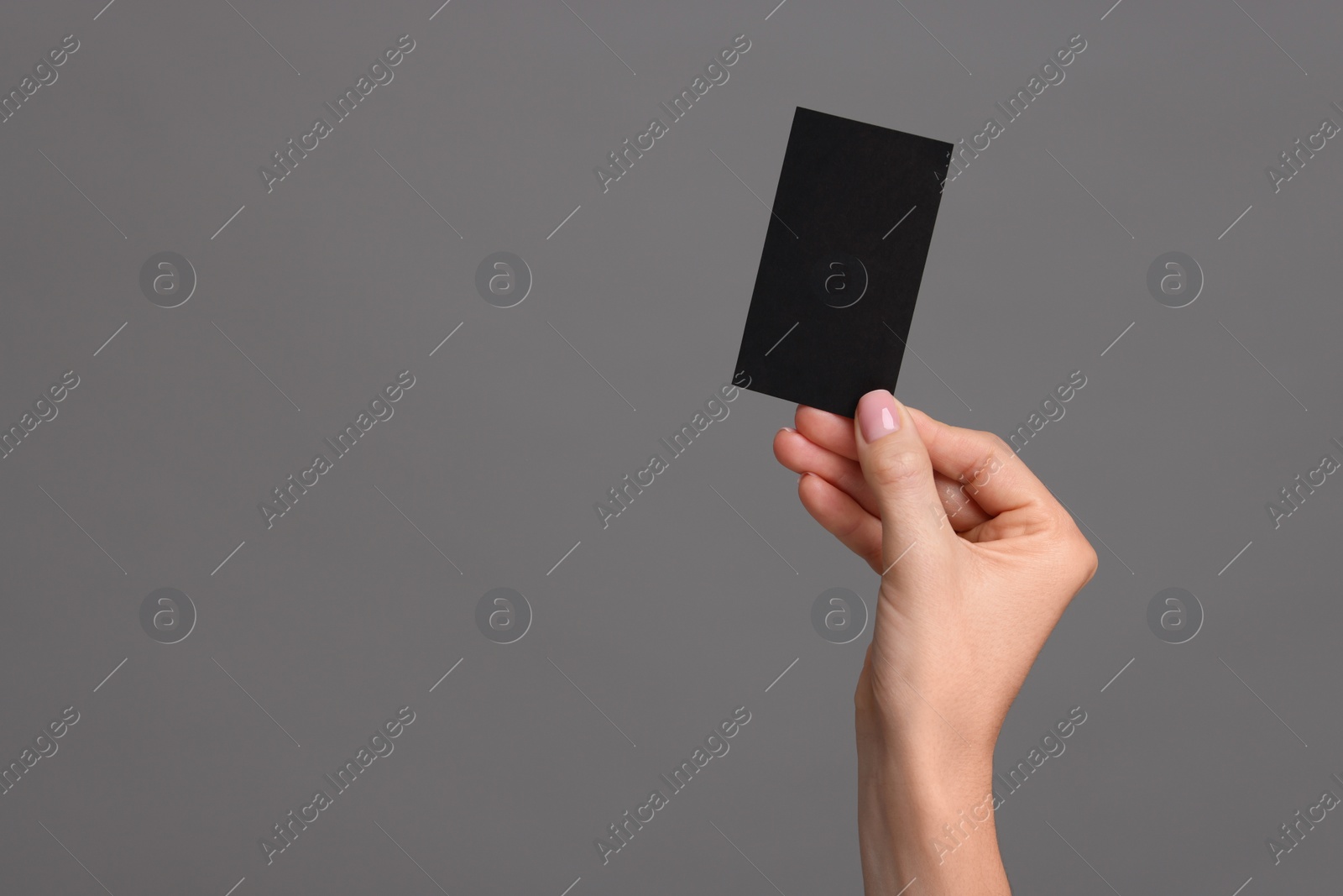 Photo of Woman holding blank business card on grey background, closeup. Space for text