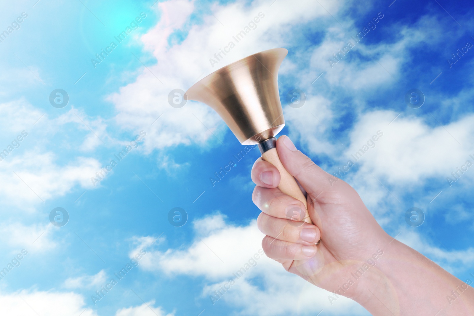 Image of Woman with school bell against blue sky, closeup