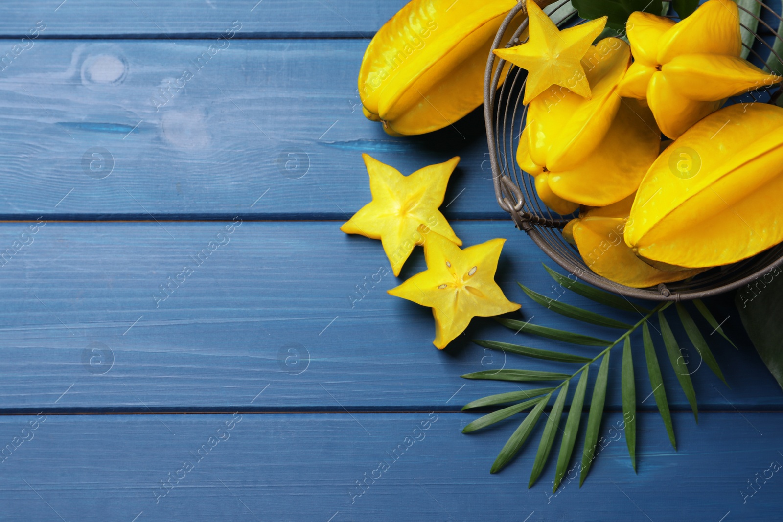 Photo of Delicious carambola fruits on blue wooden table, flat lay. Space for text