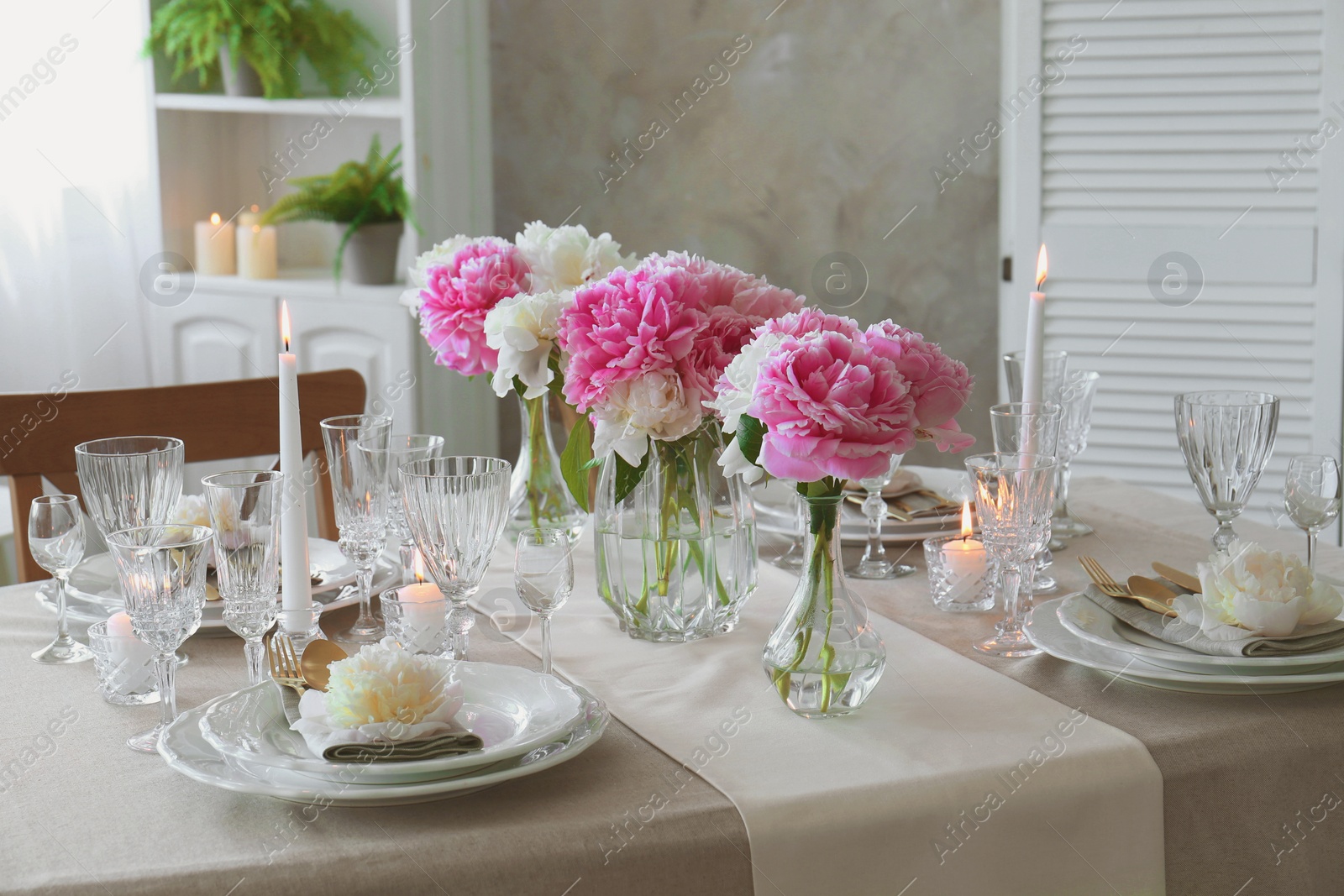 Photo of Stylish table setting with beautiful peonies and burning candles indoors