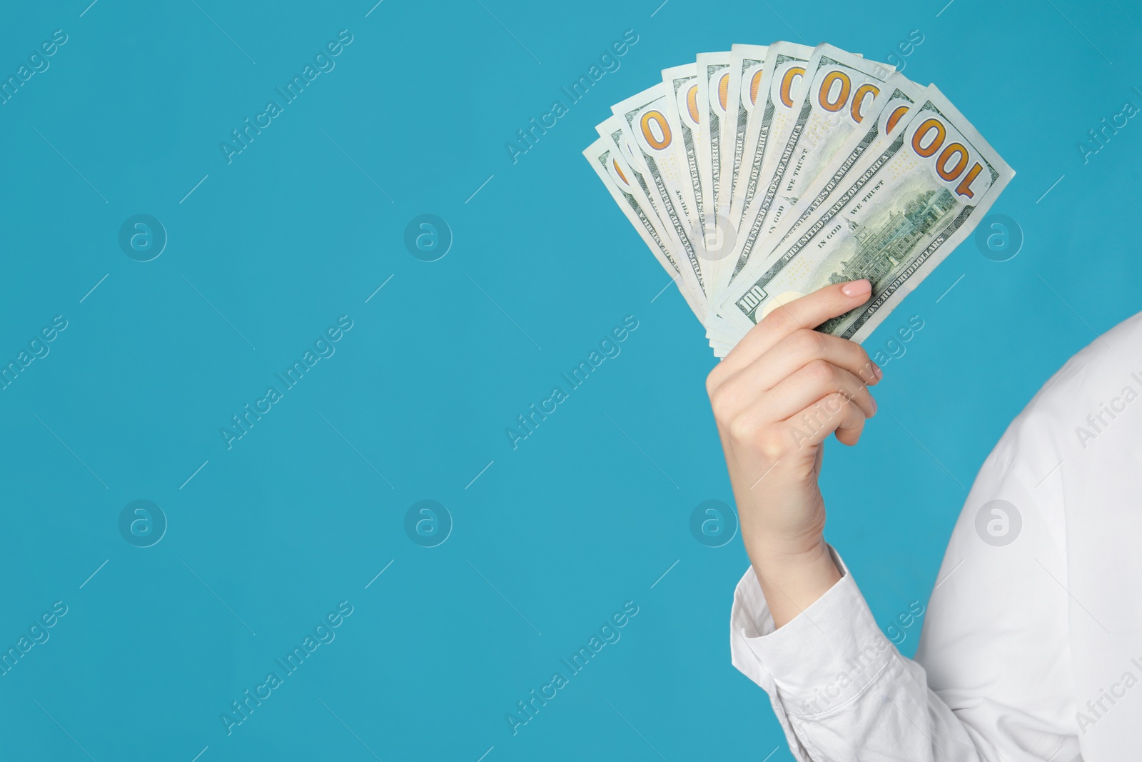Photo of Woman holding dollar banknotes on turquoise background, closeup with space for text. Money exchange concept