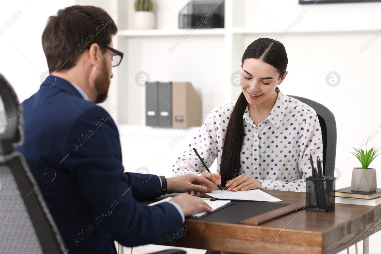 Photo of Woman signing document in lawyer's office, selective focus