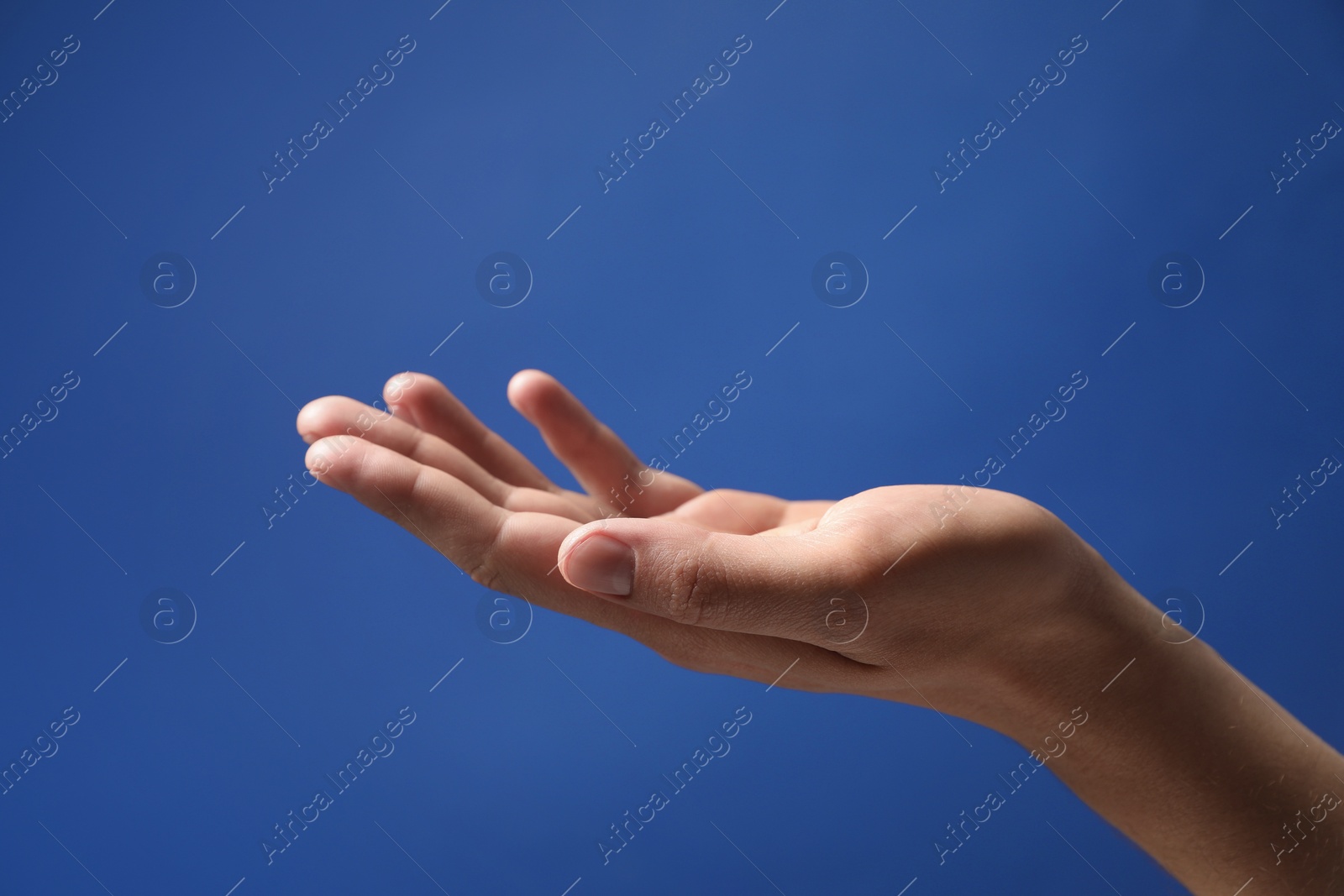 Photo of Man holding something in hand on blue background, closeup