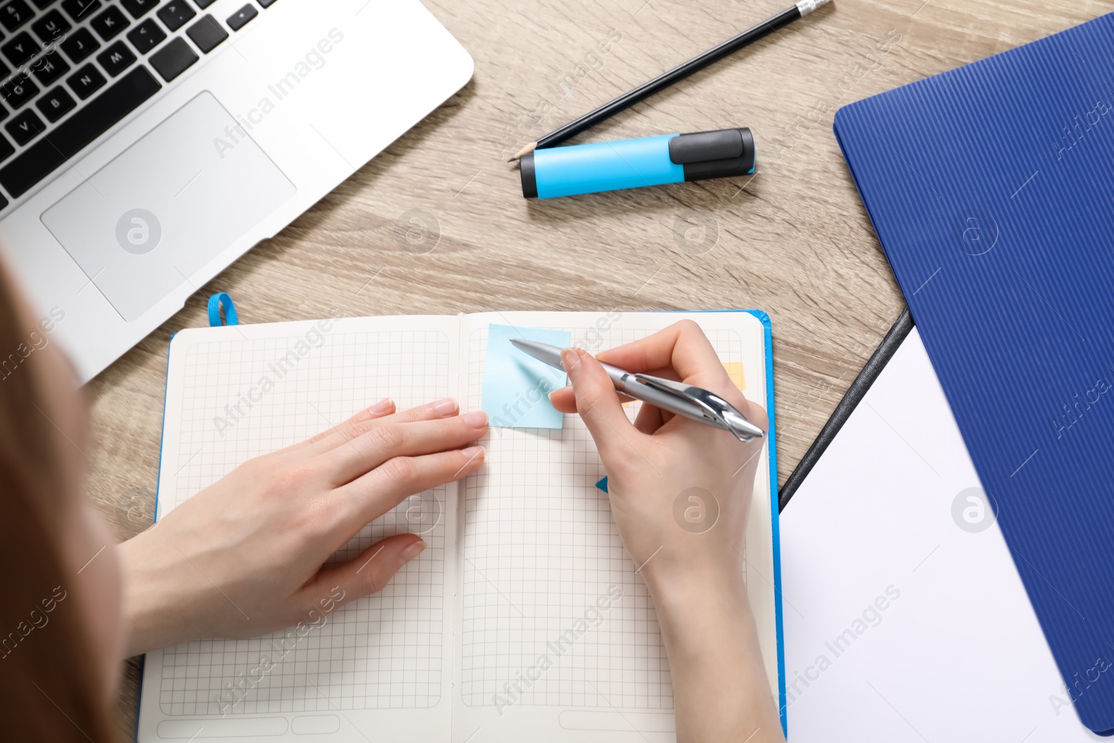 Photo of Woman taking notes at wooden table, above view