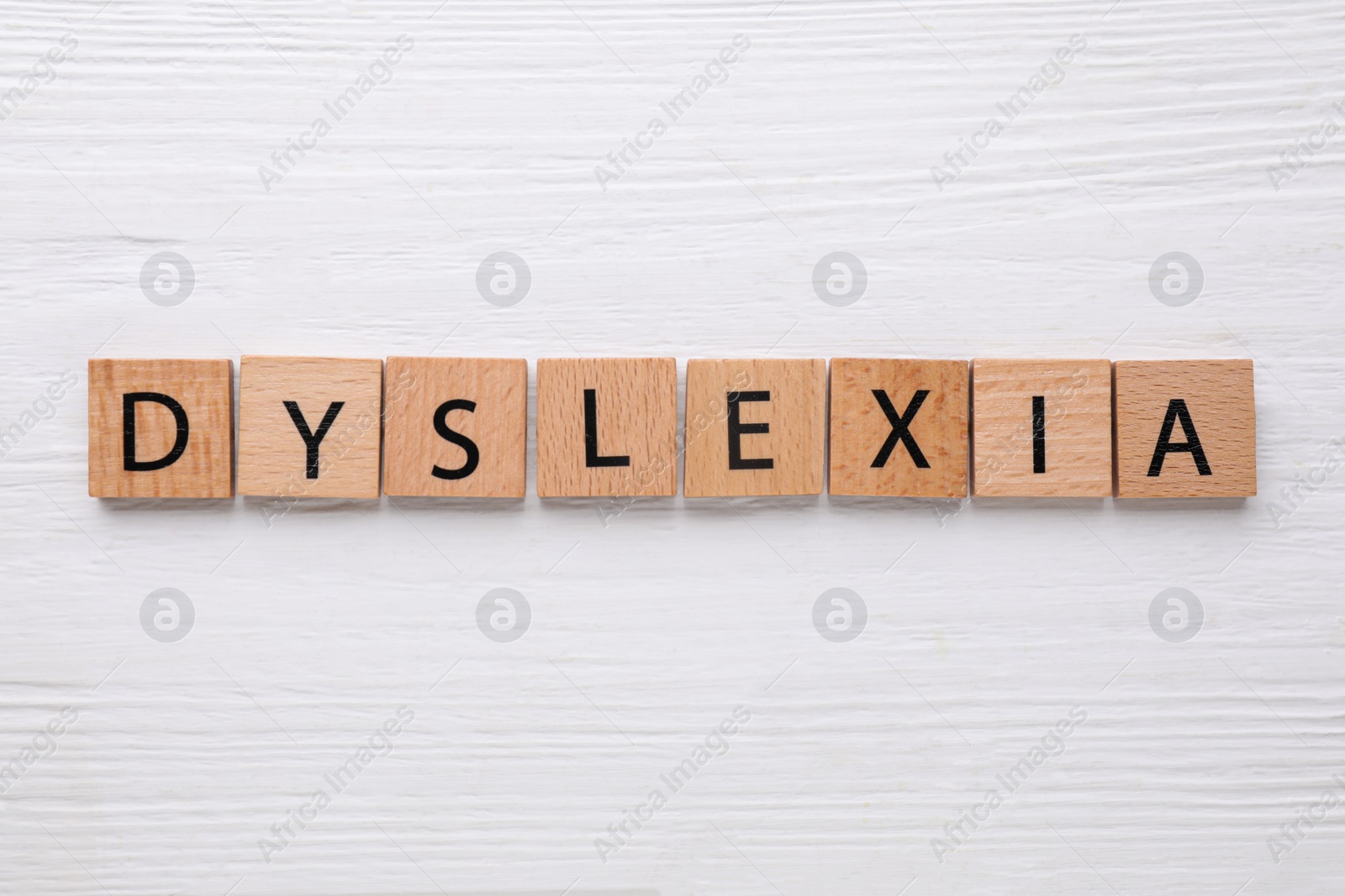 Photo of Tiles with word Dyslexia on white wooden table, flat lay