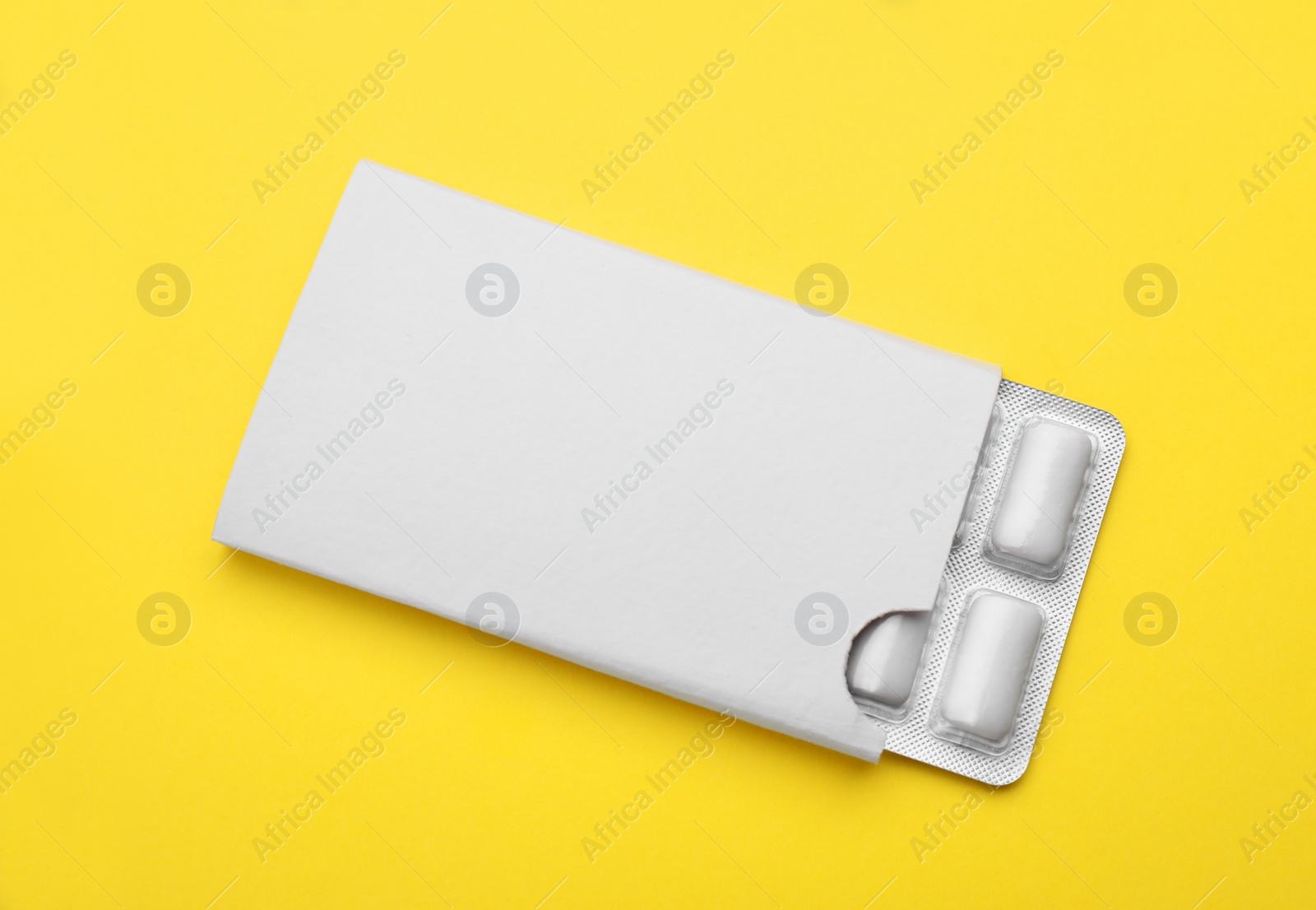 Photo of Blister with chewing gums on yellow background, top view
