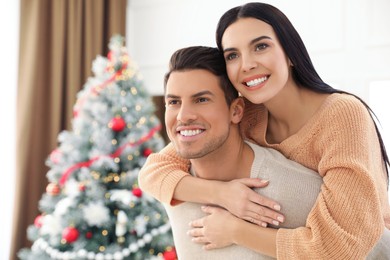 Happy couple near Christmas tree at home