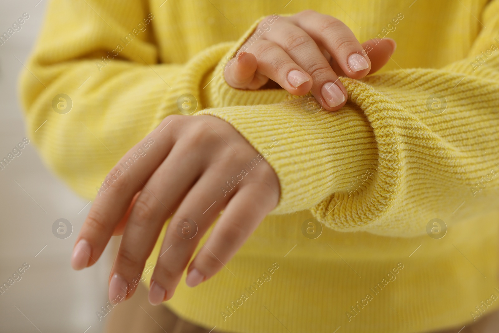 Photo of Woman touching sweater made of soft yellow fabric, closeup