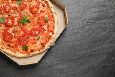 Photo of Delicious pizza Margherita on dark grey table, top view. Space for text
