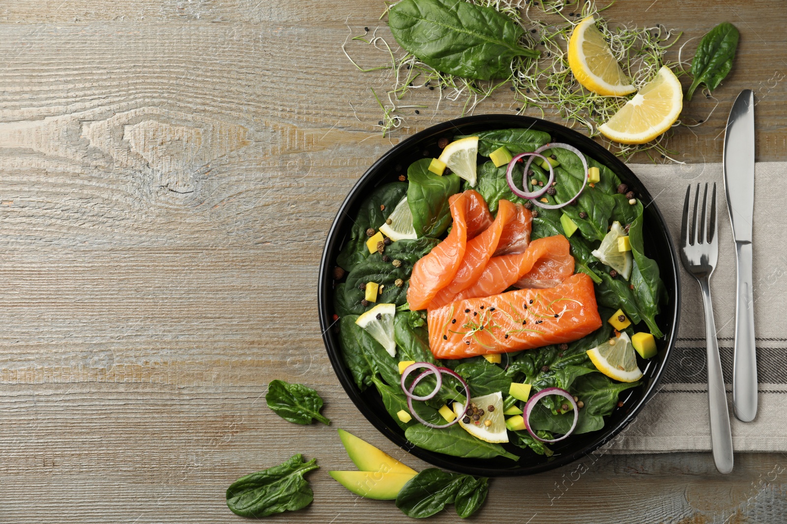 Photo of Delicious fresh salmon with spinach served on wooden table, flat lay. Space for text