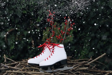 Photo of Snow falling on pair of ice skates and Christmas decor outdoors