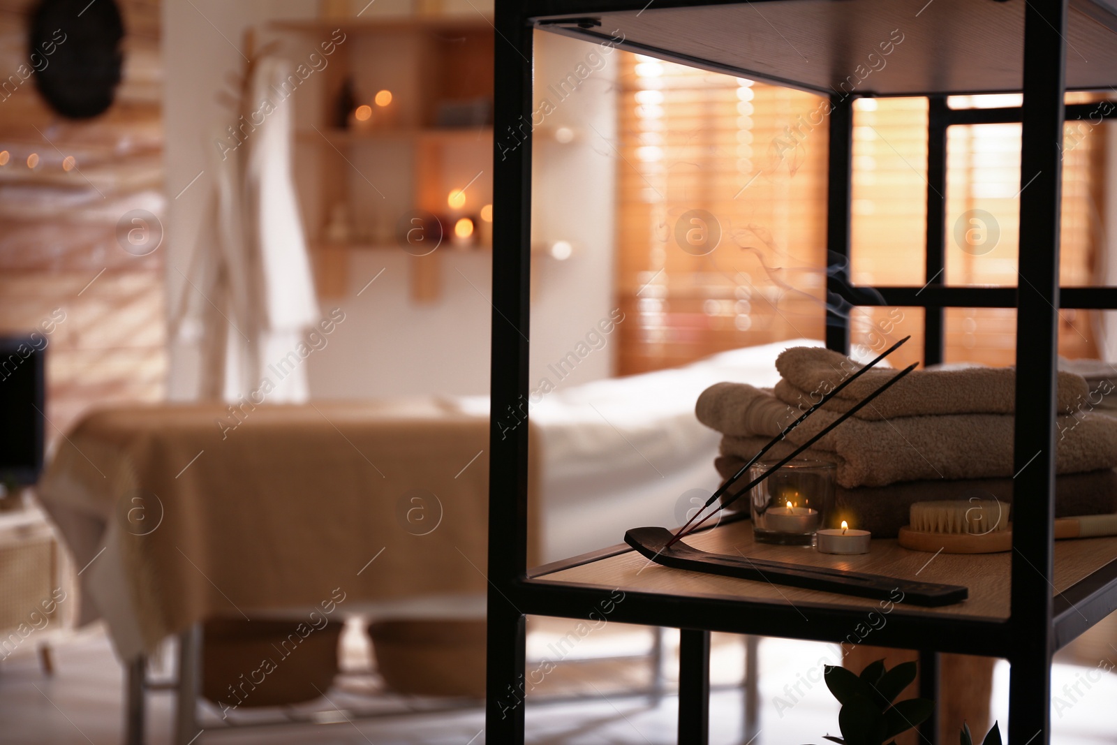 Photo of Aromatic incense sticks, burning candles and towels in spa salon. Interior design