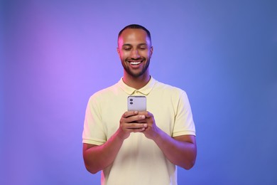 Photo of Happy man sending message via smartphone on color background