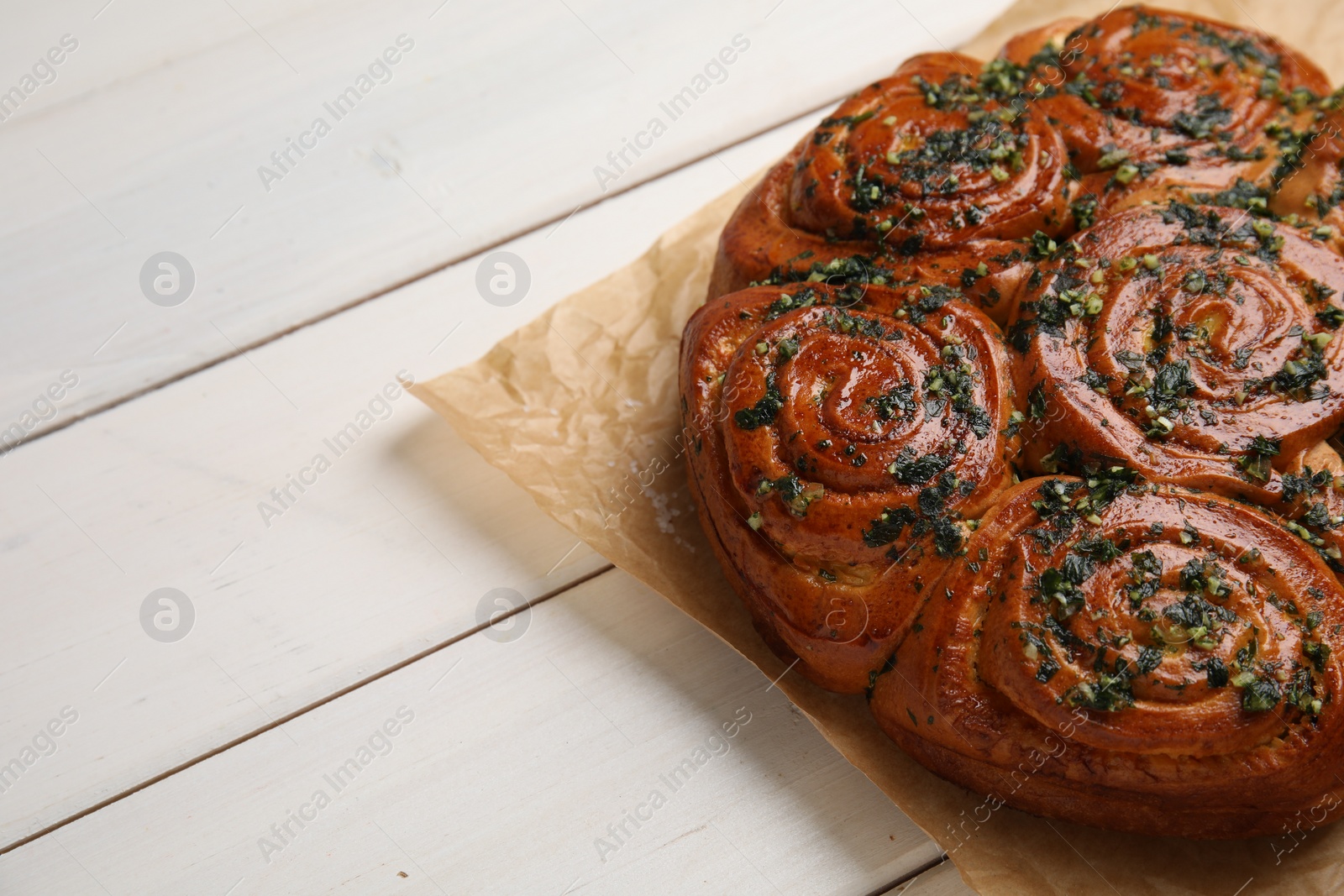 Photo of Traditional pampushka rolls with garlic and herbs on white wooden table. Space for text