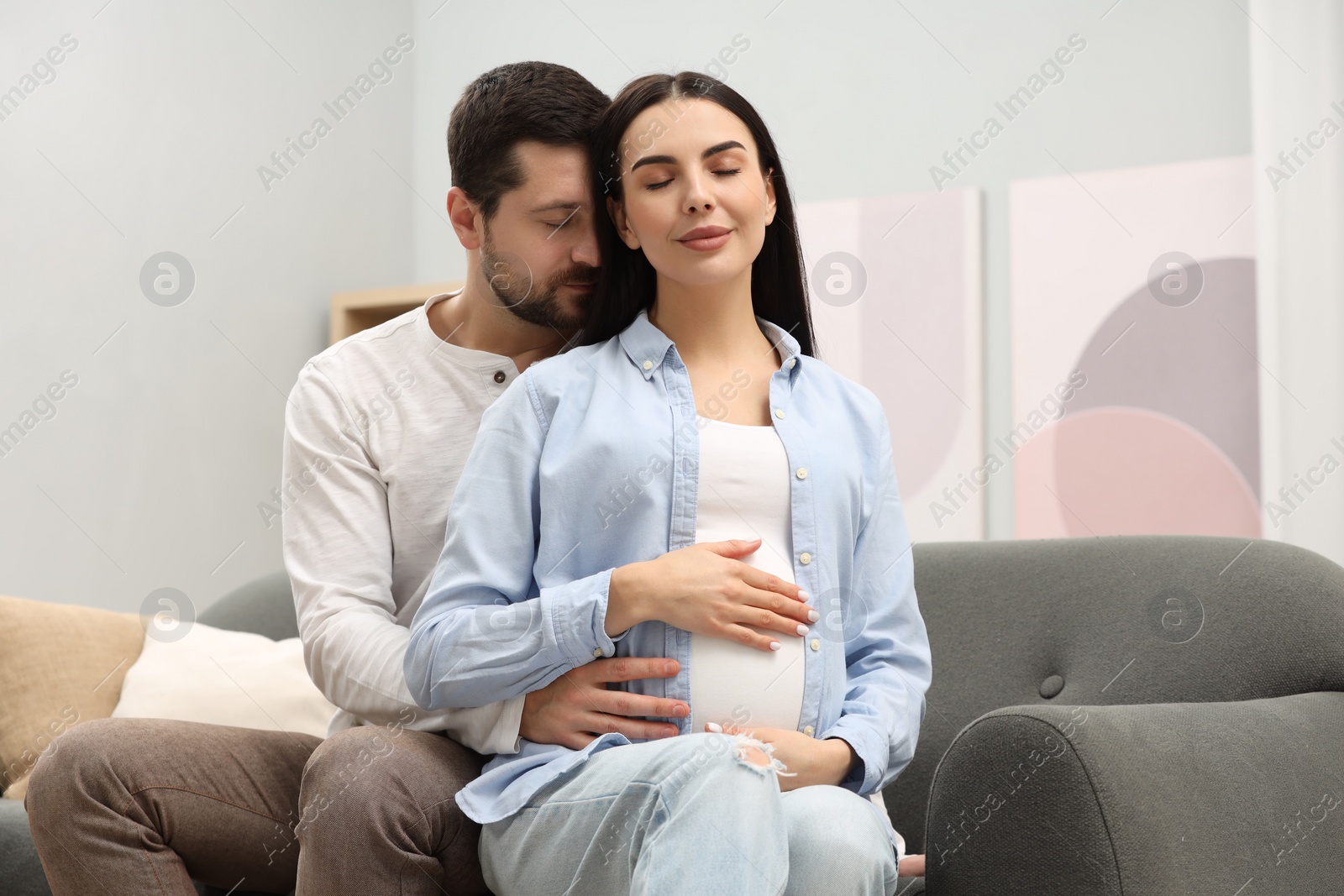 Photo of Pregnant woman with her husband on sofa at home