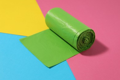 Photo of Roll of green garbage bags on color background