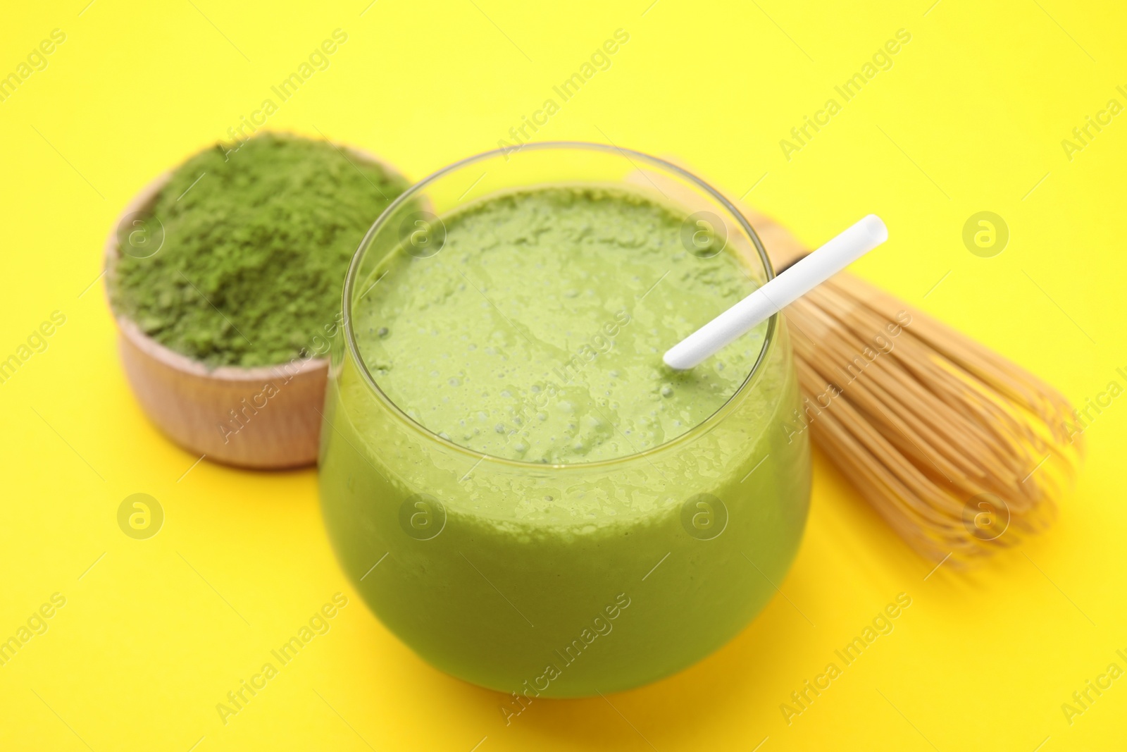 Photo of Glass of tasty matcha smoothie on yellow background, closeup