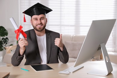 Happy student with graduation hat and diploma at workplace in office