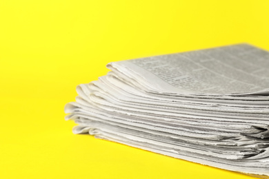 Photo of Stack of newspapers on yellow background, closeup. Journalist's work