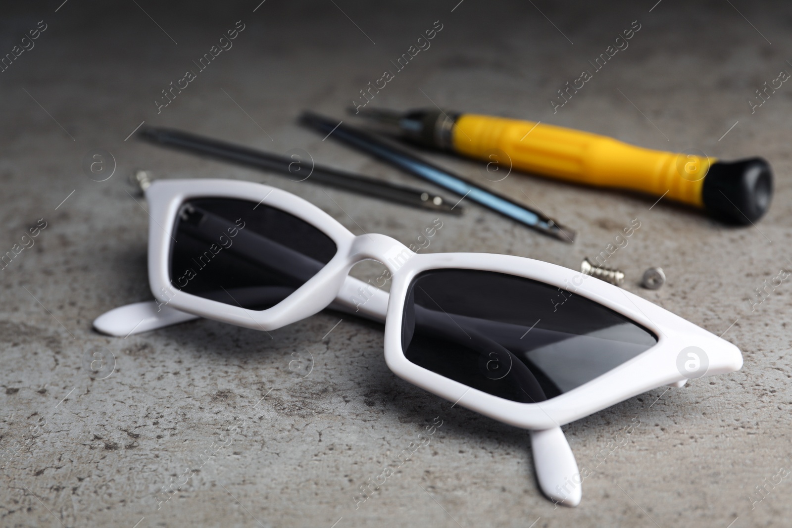 Photo of Stylish female sunglasses and fixing tools on grey table